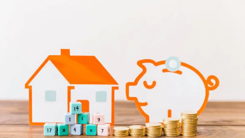 Mô hình ngôi nhà, heo đất và đồng xu minh họa điều kiện thu nhập