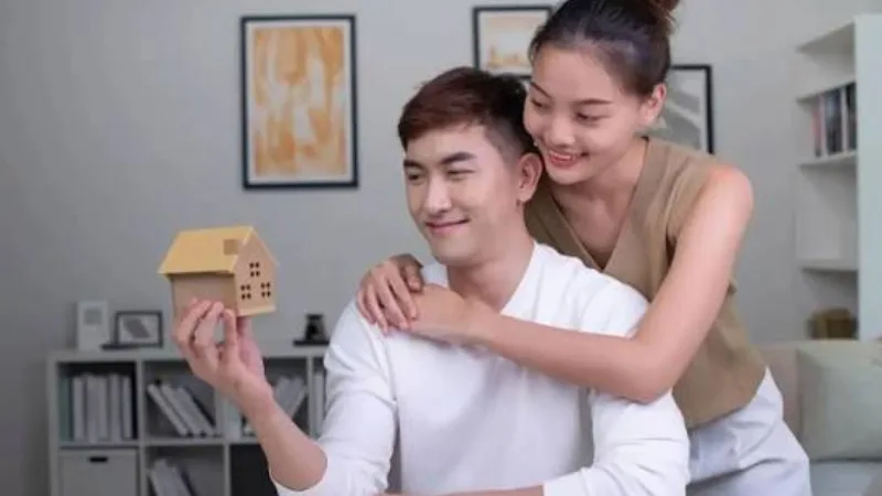Cặp vợ chồng trẻ cầm mô hình ngôi nhà