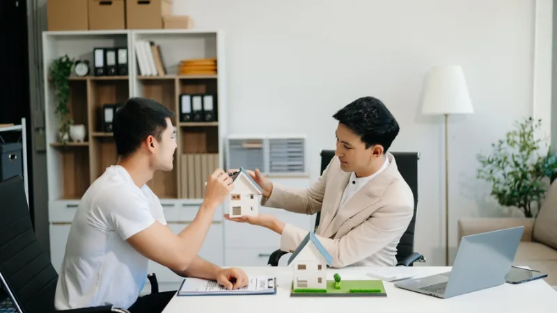 Nhân viên tư vấn khoản vay trao đổi với khách hàng bên mô hình nhà