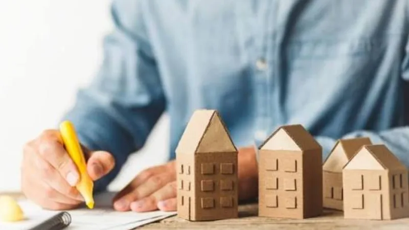 Người ghi chép bên các mô hình nhà bằng giấy
